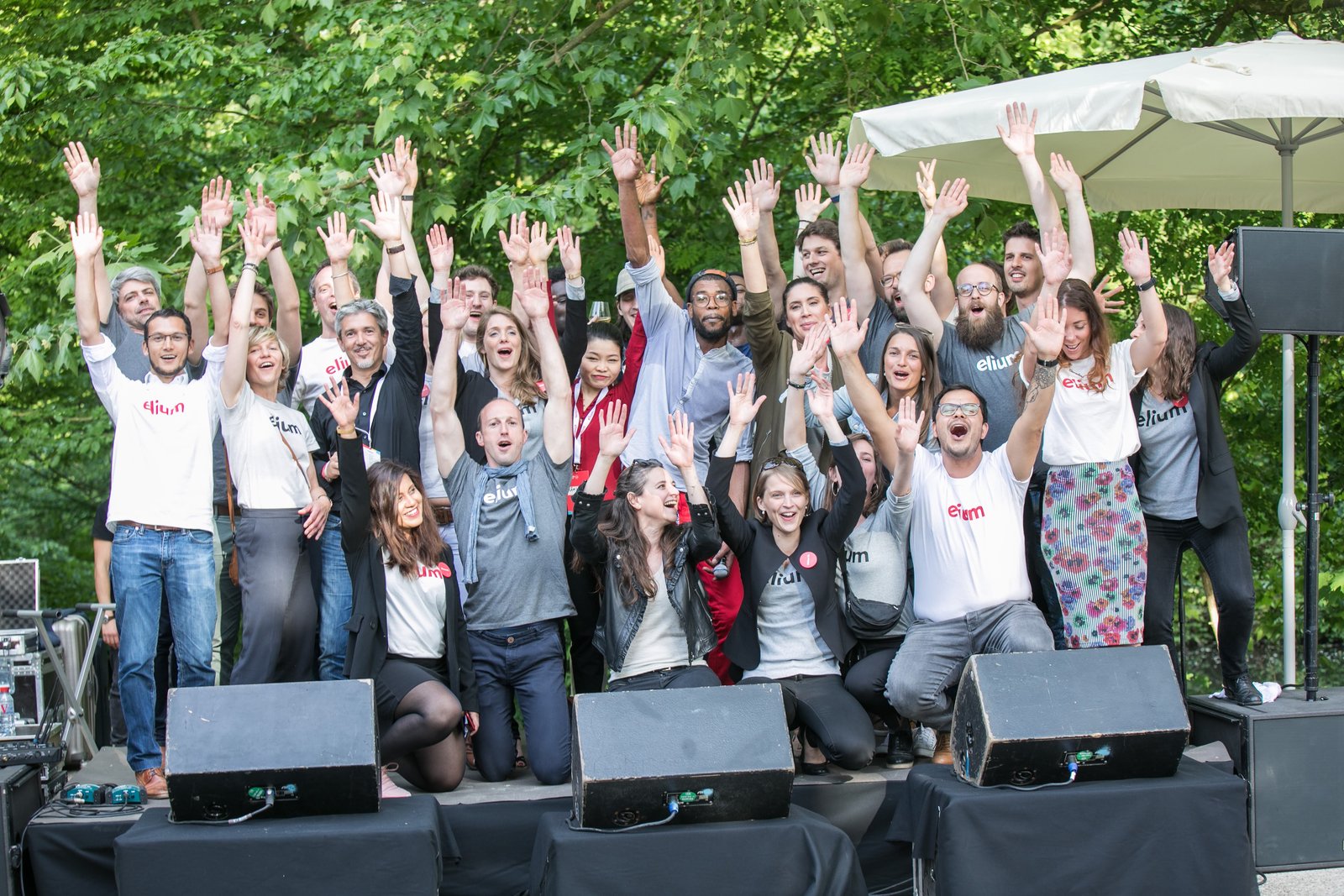 The Elium team celebrating on stage, arms in the air
